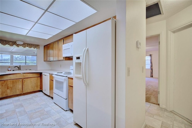 kitchen with visible vents, a sink, white appliances, light countertops, and a healthy amount of sunlight