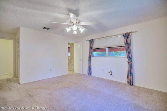 carpeted empty room with a ceiling fan, visible vents, and a textured ceiling