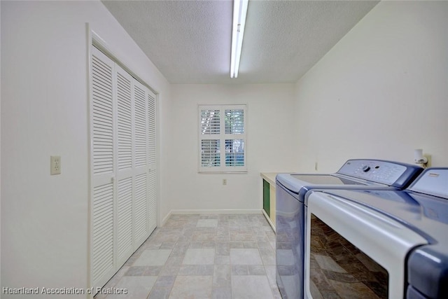 clothes washing area featuring washer and clothes dryer, laundry area, a textured ceiling, and baseboards