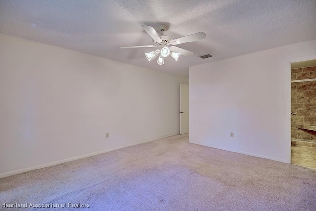 unfurnished room featuring baseboards, visible vents, ceiling fan, a textured ceiling, and light colored carpet