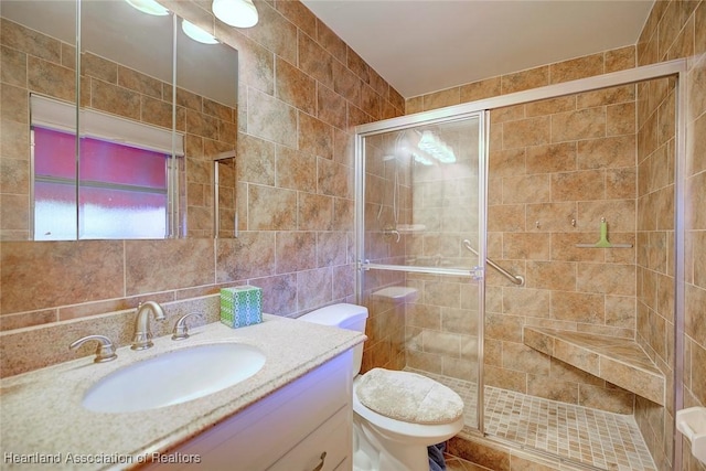 full bath featuring toilet, tile walls, a stall shower, and vanity