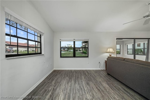 unfurnished living room featuring a wealth of natural light, dark hardwood / wood-style floors, ceiling fan, and vaulted ceiling