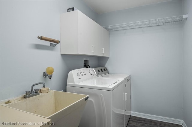 washroom featuring cabinets, sink, washing machine and clothes dryer, and dark hardwood / wood-style flooring