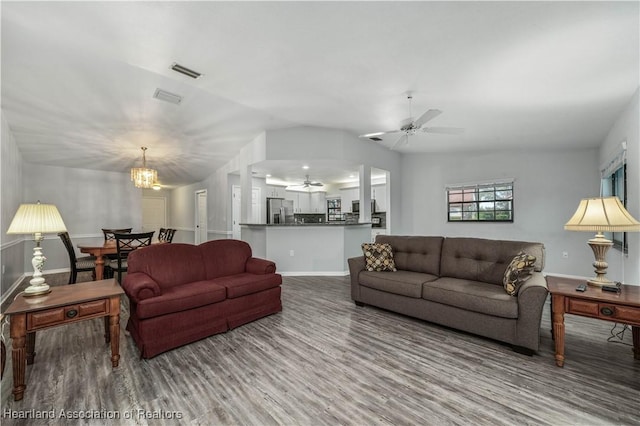 living room with hardwood / wood-style floors, lofted ceiling, and ceiling fan with notable chandelier