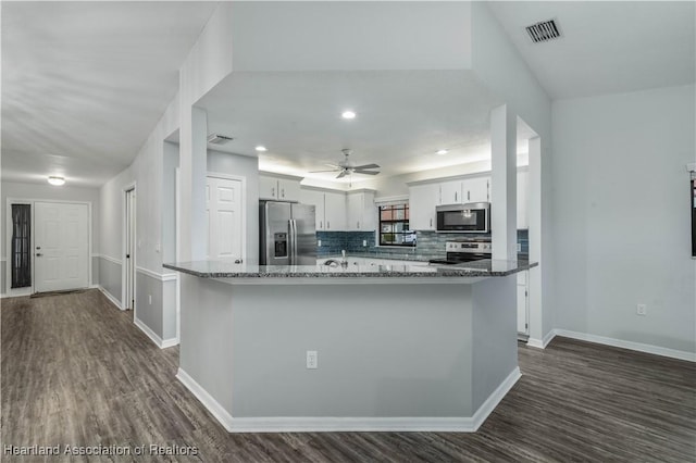 kitchen with appliances with stainless steel finishes, tasteful backsplash, white cabinets, dark hardwood / wood-style flooring, and dark stone counters