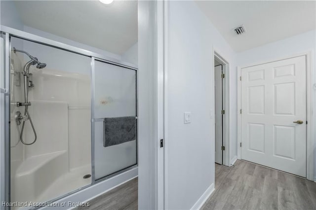 bathroom featuring an enclosed shower and wood-type flooring