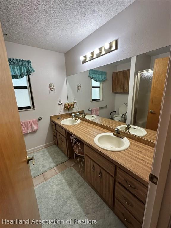 full bathroom with a stall shower, double vanity, and a sink