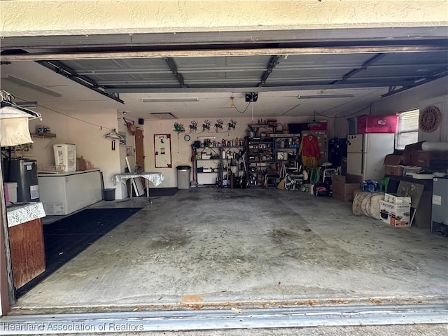 garage featuring electric water heater and freestanding refrigerator