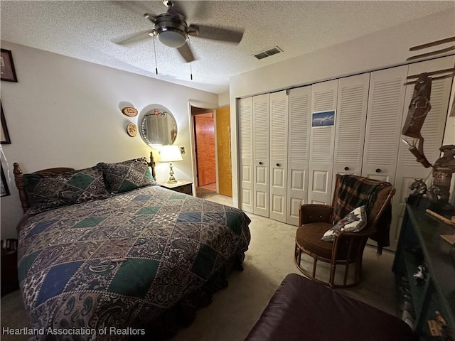 bedroom with a textured ceiling, a closet, carpet flooring, and visible vents