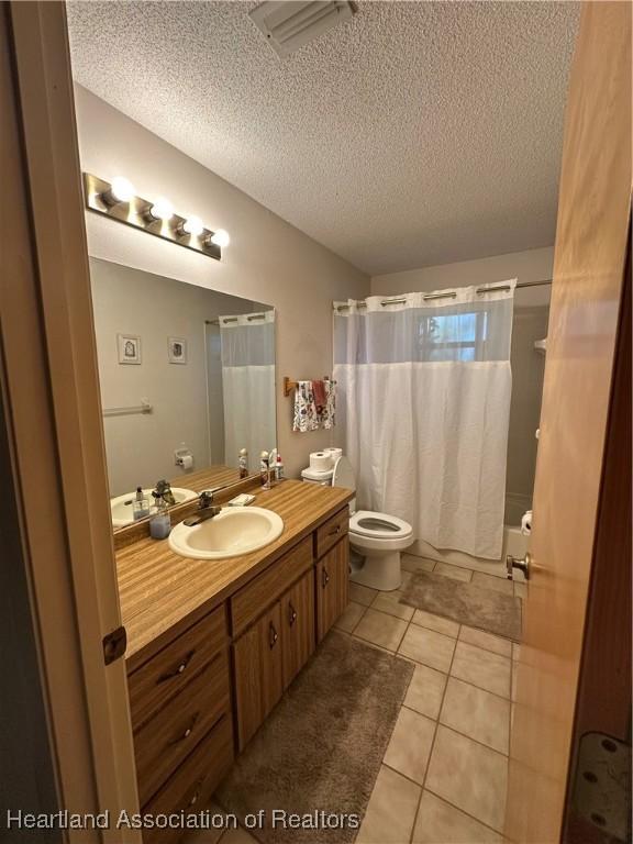 full bath with toilet, a textured ceiling, vanity, and tile patterned flooring