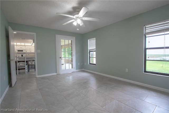 tiled empty room with a textured ceiling and ceiling fan