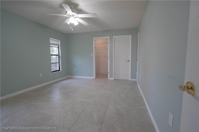 unfurnished bedroom featuring a walk in closet, ceiling fan, a closet, and a textured ceiling