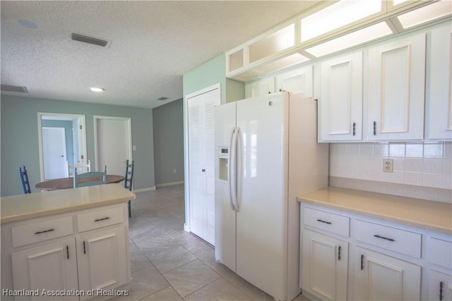 kitchen with decorative backsplash, white cabinetry, white fridge with ice dispenser, and a textured ceiling