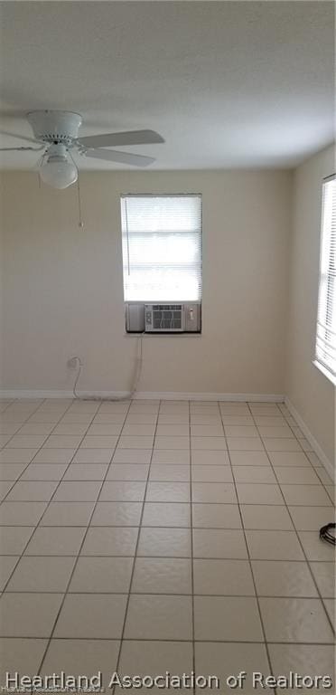 tiled spare room with a wealth of natural light, cooling unit, and ceiling fan