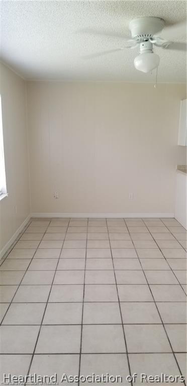 tiled spare room featuring a textured ceiling and ceiling fan