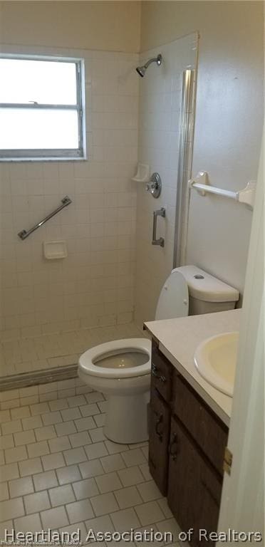 bathroom featuring tiled shower, vanity, tile patterned floors, and toilet