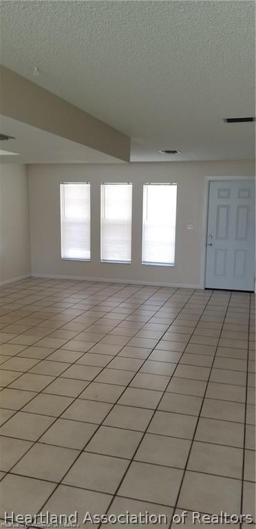 tiled spare room featuring a textured ceiling