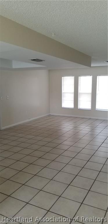 tiled spare room featuring a textured ceiling