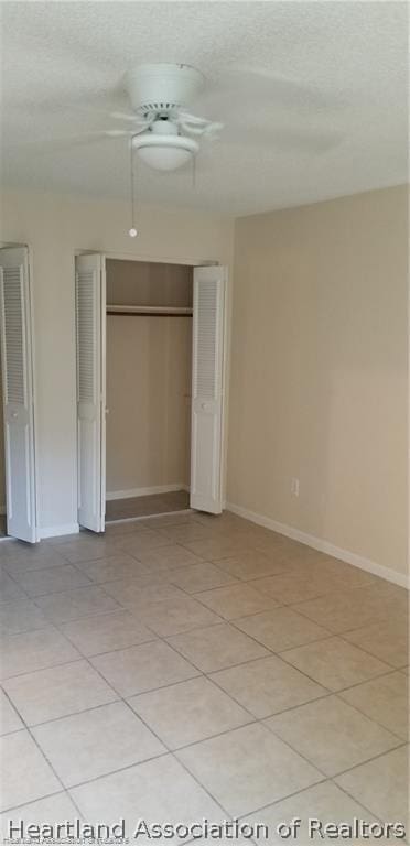 unfurnished bedroom featuring light tile patterned floors, a closet, and ceiling fan