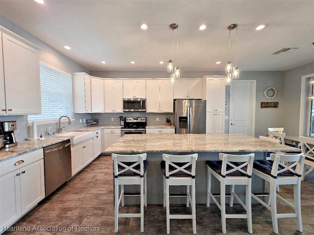 132 Red Water Pt, Lake Placid, FL 33852 - kitchen featuring appliances with stainless steel finishes, a kitchen island, white cabinets, tasteful backsplash, and recessed lighting