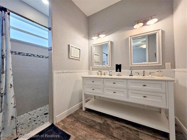 132 Red Water Pt, Lake Placid, FL 33852 - bathroom featuring wood finished floors, double vanity, tiled shower, wainscoting, and a textured wall