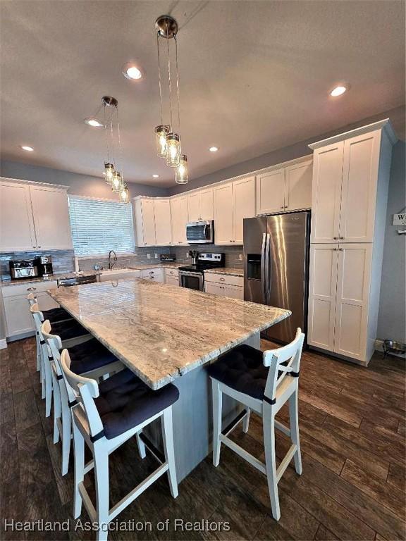 132 Red Water Pt, Lake Placid, FL 33852 - kitchen featuring stainless steel appliances, white cabinets, backsplash, a kitchen island, and light stone countertops