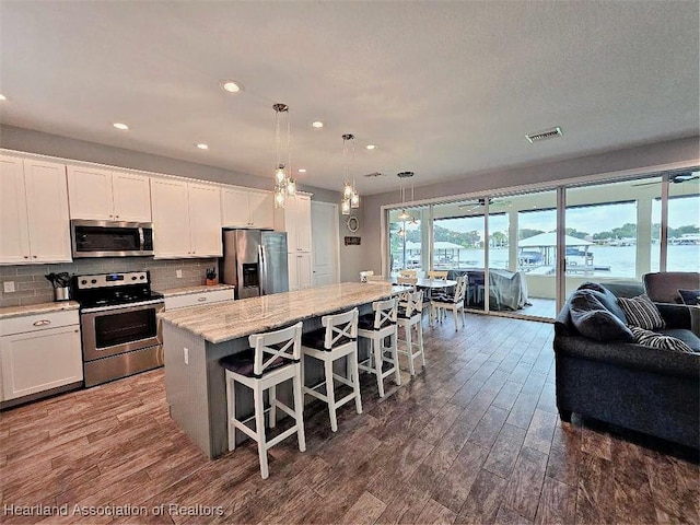 132 Red Water Pt, Lake Placid, FL 33852 - kitchen featuring appliances with stainless steel finishes, open floor plan, a center island, dark wood finished floors, and white cabinets