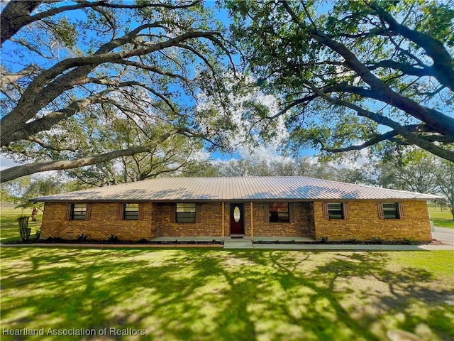 single story home with metal roof, a front lawn, and brick siding