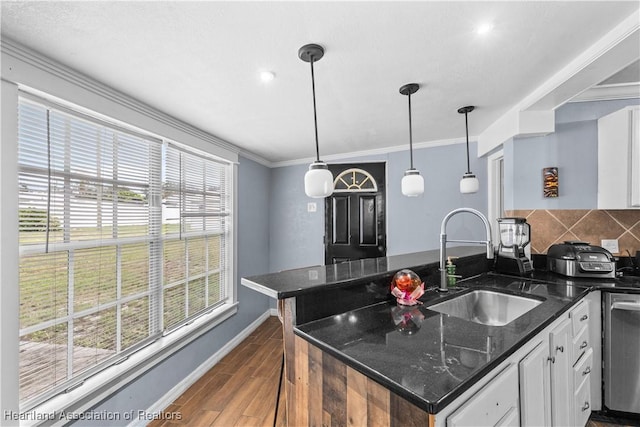 kitchen with white cabinets, decorative light fixtures, sink, and dark stone counters