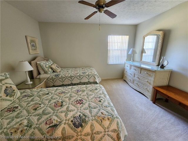 bedroom featuring ceiling fan, light colored carpet, and a textured ceiling