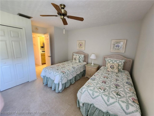 bedroom featuring light colored carpet, a closet, and ceiling fan