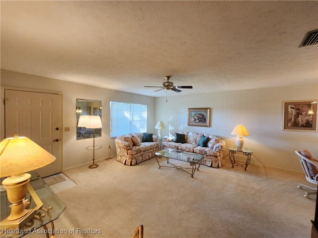 living room featuring ceiling fan, light colored carpet, and a textured ceiling