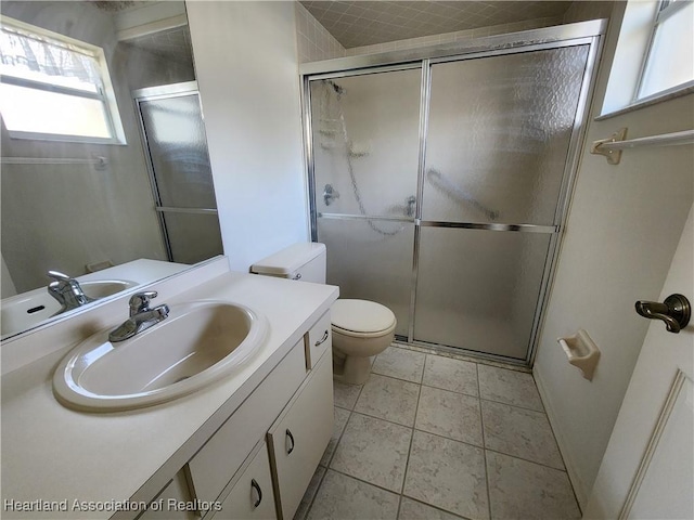 bathroom with vanity, toilet, a shower with shower door, and tile patterned flooring