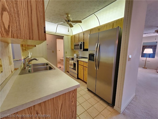 kitchen featuring sink, ceiling fan, stainless steel appliances, a textured ceiling, and light colored carpet