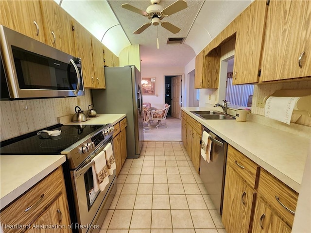 kitchen with lofted ceiling, light tile patterned floors, sink, ceiling fan, and stainless steel appliances