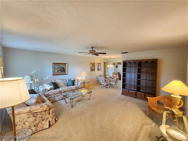 carpeted living room with ceiling fan and a textured ceiling