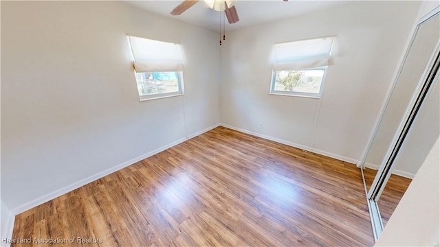 unfurnished bedroom with a ceiling fan, wood finished floors, and baseboards