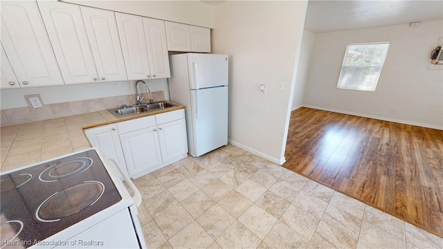 kitchen featuring baseboards, tile countertops, white cabinets, white appliances, and a sink