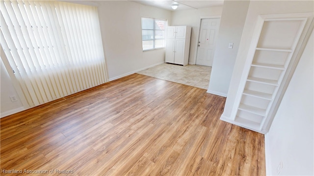 unfurnished room with baseboards and light wood finished floors