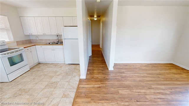 kitchen featuring white appliances, baseboards, a sink, light countertops, and white cabinetry