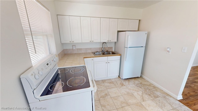 kitchen featuring baseboards, light countertops, white cabinets, white appliances, and a sink