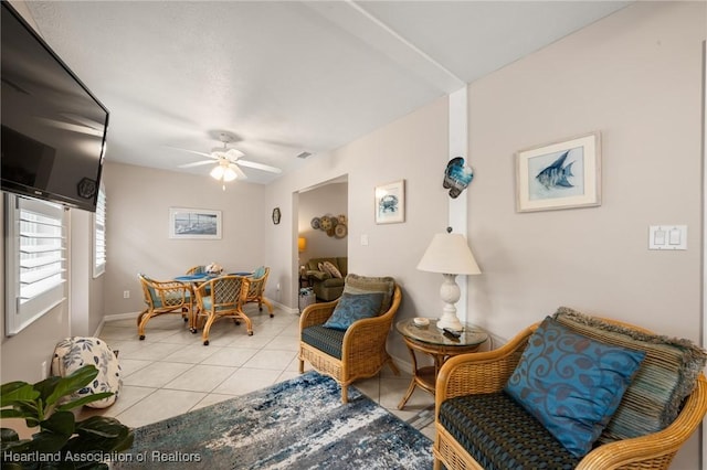 sitting room with light tile patterned floors, visible vents, baseboards, and ceiling fan