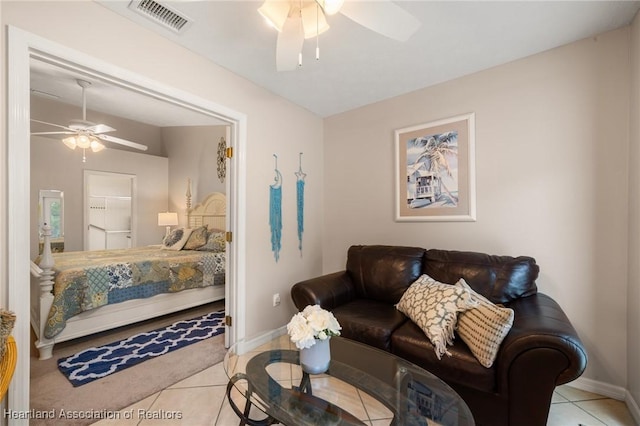 living area with light tile patterned floors, visible vents, baseboards, and ceiling fan