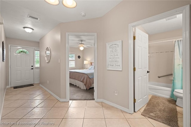 foyer entrance featuring visible vents, baseboards, ceiling fan, and light tile patterned flooring