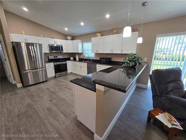 kitchen featuring kitchen peninsula, sink, stainless steel appliances, and decorative light fixtures