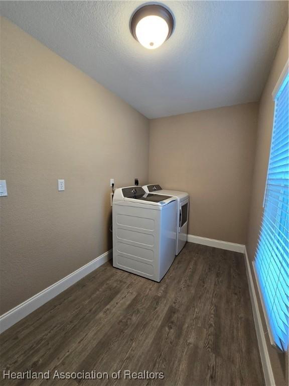 clothes washing area with a textured ceiling, dark hardwood / wood-style flooring, and washing machine and clothes dryer