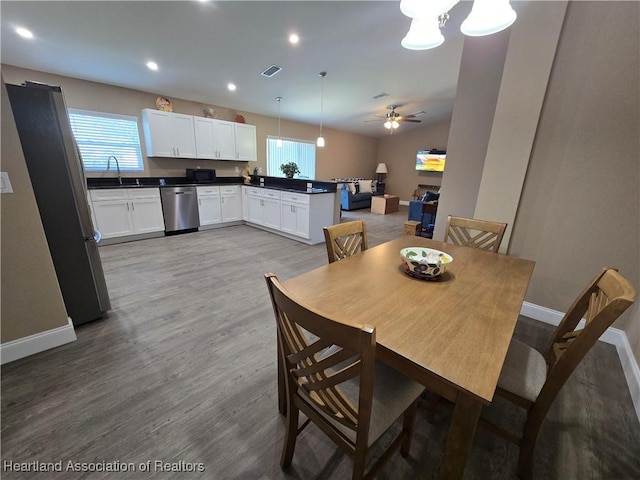 dining room featuring ceiling fan, light hardwood / wood-style flooring, vaulted ceiling, and sink