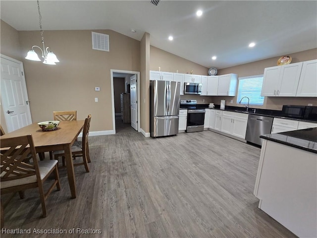 kitchen with decorative light fixtures, stainless steel appliances, white cabinetry, and sink