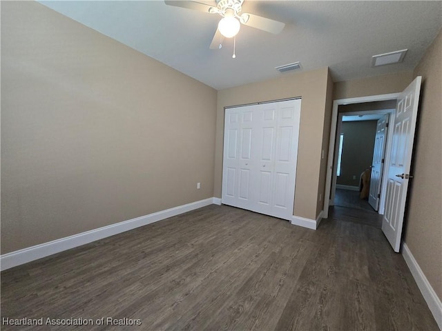 unfurnished bedroom with dark hardwood / wood-style flooring, a closet, and ceiling fan