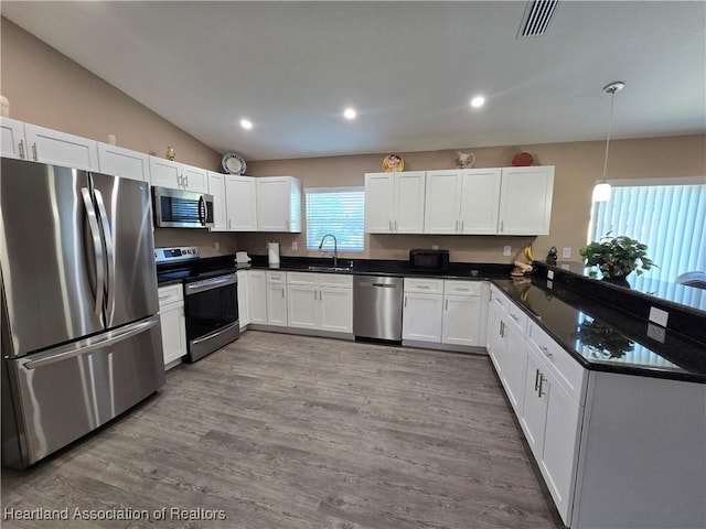 kitchen with stainless steel appliances, sink, decorative light fixtures, light hardwood / wood-style floors, and white cabinetry